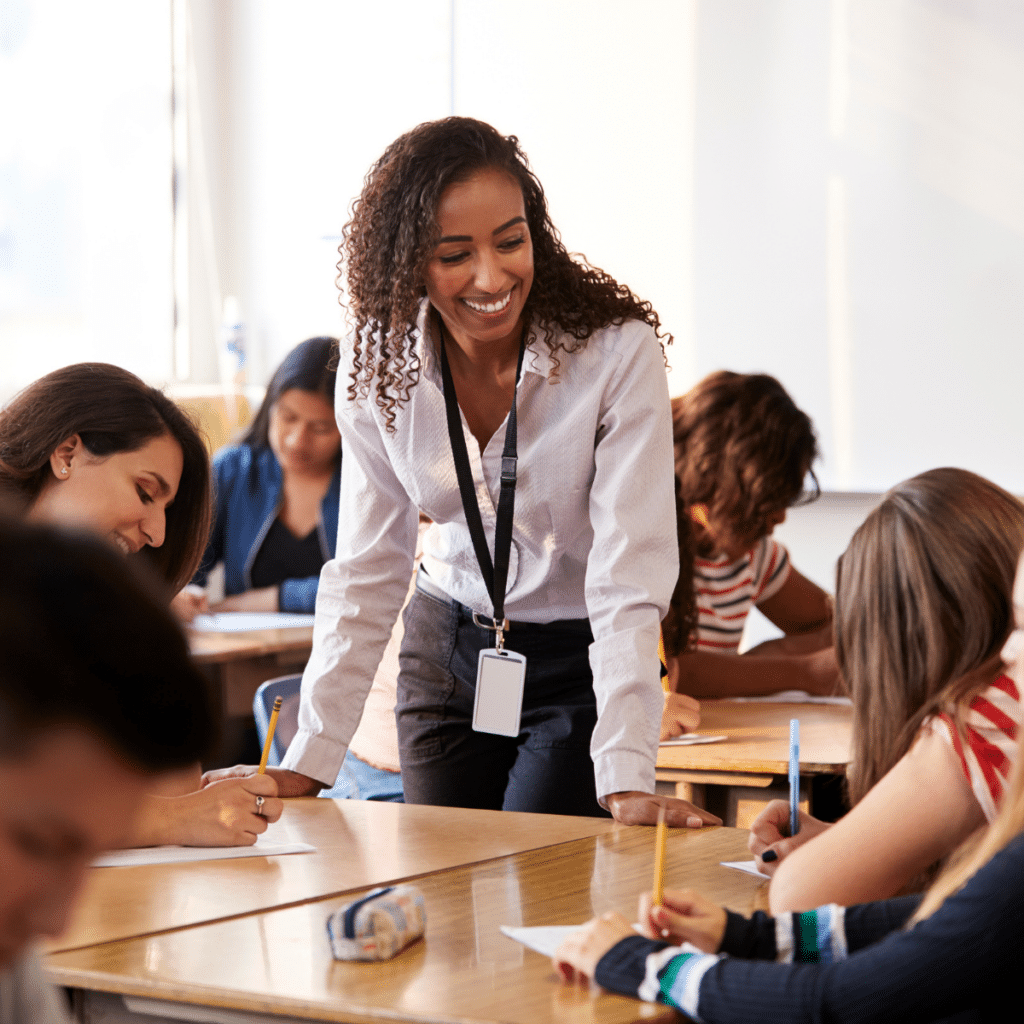 A woman standing around a table helping students with their work