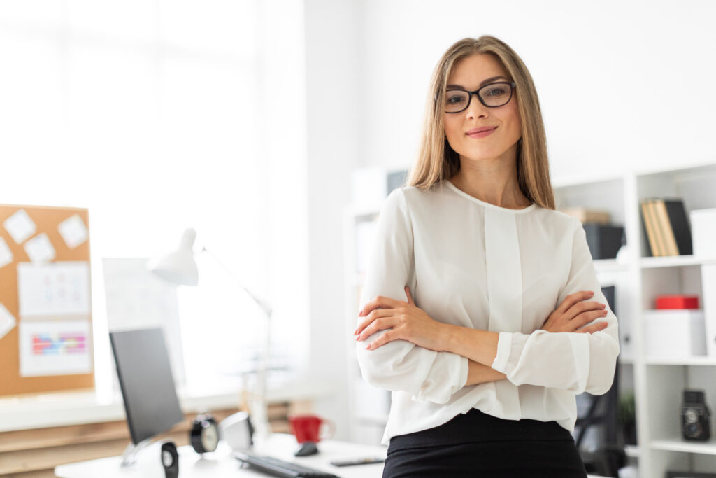 A young girl is standing leaning on a table in the office.