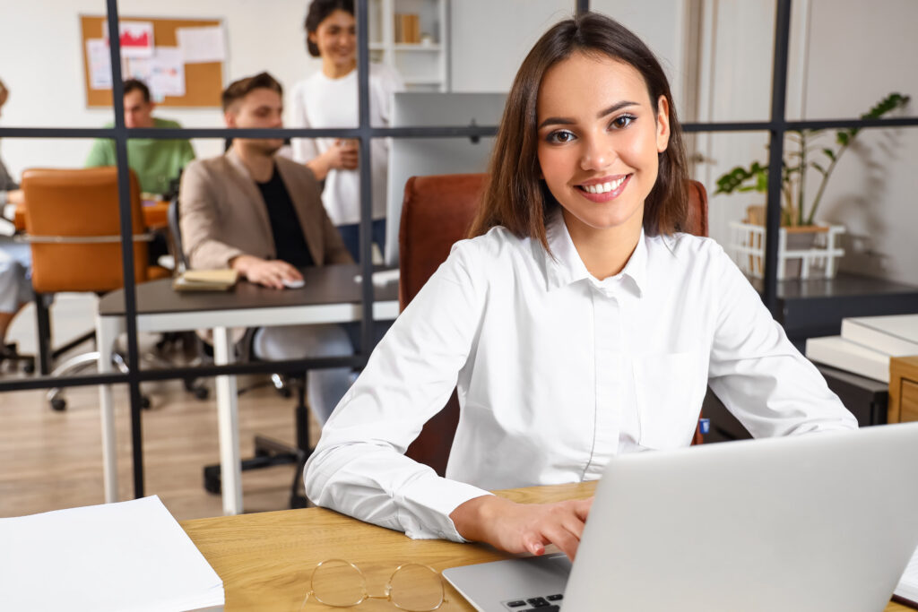 Young business woman working with laptop at table in office