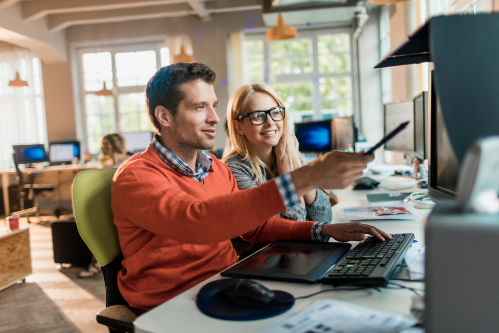 Two diverse colleagues using a computer together in the office